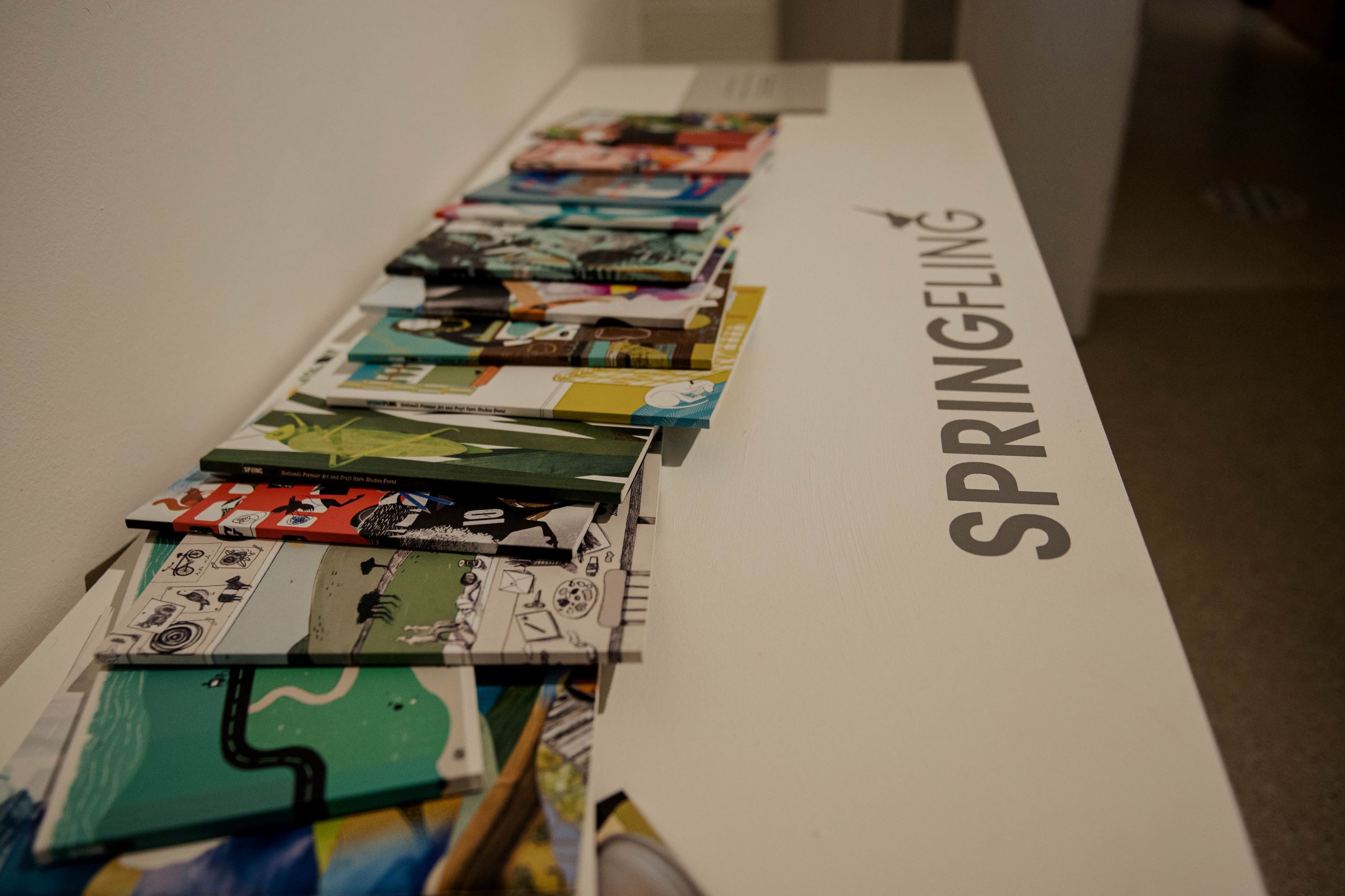 Spring Fling brochures from across the years spread across table at Spring Fling retrospective exhibition