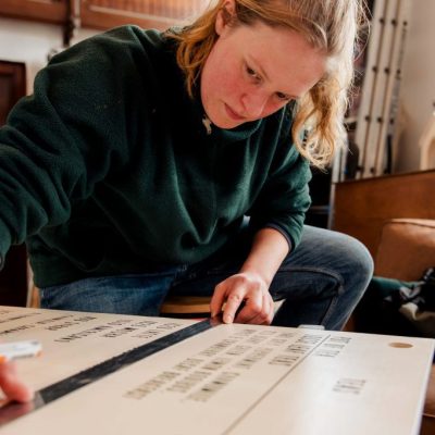 Image of the artist working on final details of a signboard. Image credit: Kirstin McEwan.